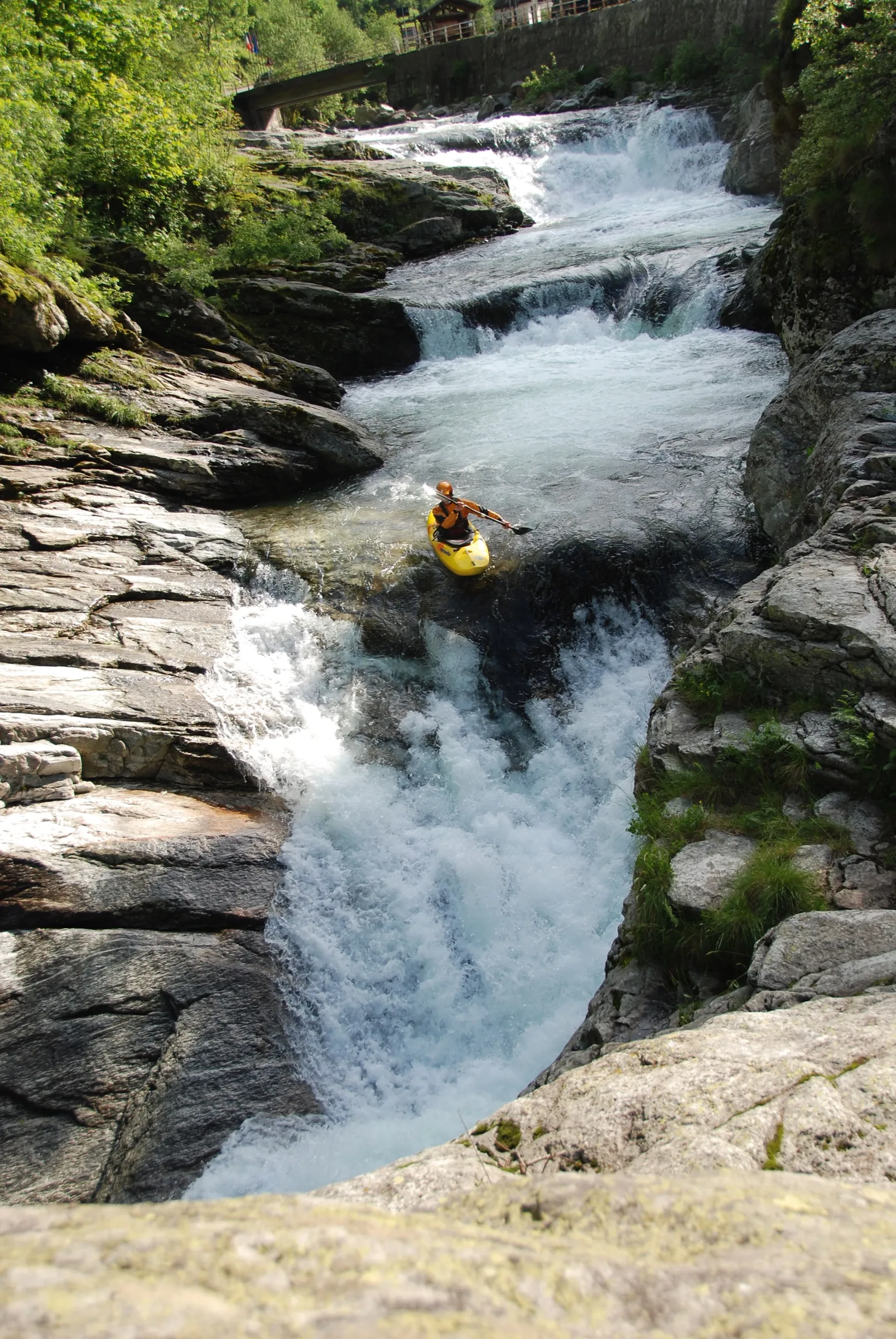 Kayaking through a rocky waterfall in a yellow kayak