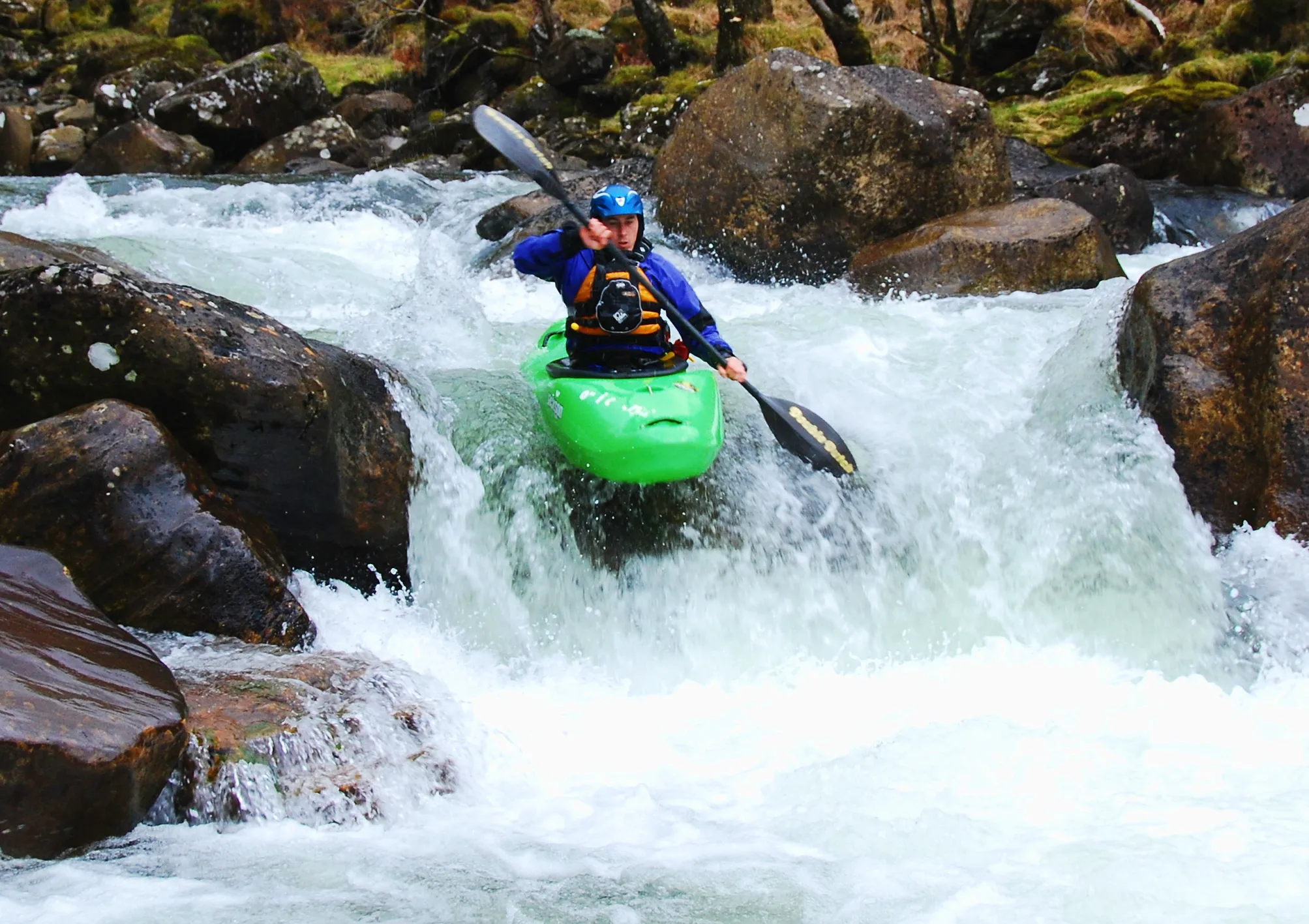 Alex paddling a green kayak through whitewater